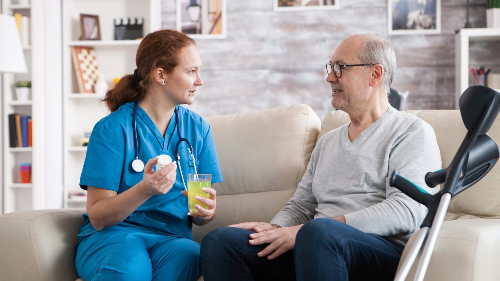 Senior man in nursing home smiling to the nurse while she's giving him pills.